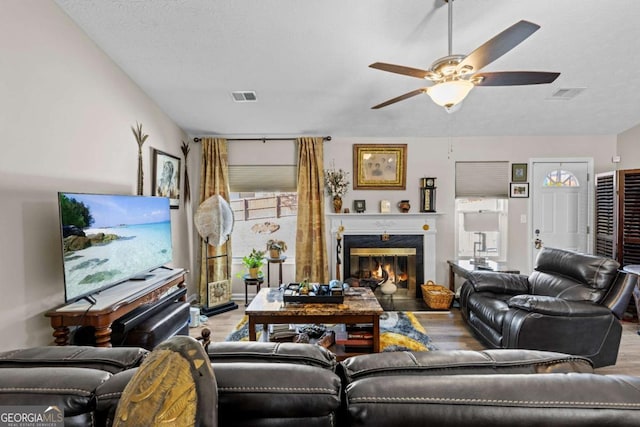 living room with ceiling fan, hardwood / wood-style floors, and a textured ceiling