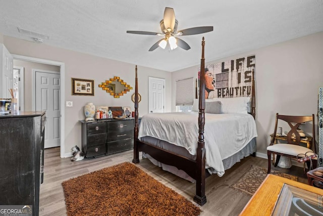 bedroom featuring ceiling fan, light hardwood / wood-style floors, and a textured ceiling