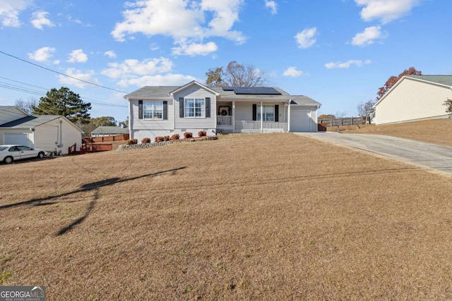 view of front of home featuring covered porch, solar panels, a garage, and a front yard