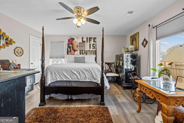 bedroom featuring ceiling fan, light hardwood / wood-style floors, and a textured ceiling