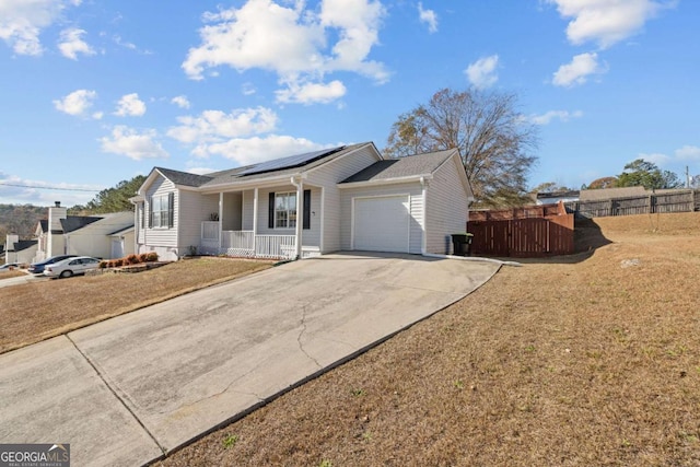 ranch-style house featuring solar panels, a porch, a garage, and a front lawn