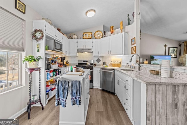 kitchen featuring sink, vaulted ceiling, light hardwood / wood-style floors, white cabinetry, and stainless steel appliances