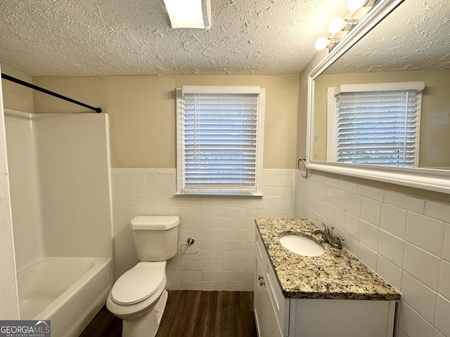 full bathroom with hardwood / wood-style floors, vanity, toilet, a textured ceiling, and tile walls