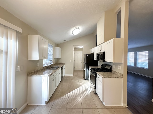 kitchen featuring plenty of natural light, white cabinetry, appliances with stainless steel finishes, and vaulted ceiling