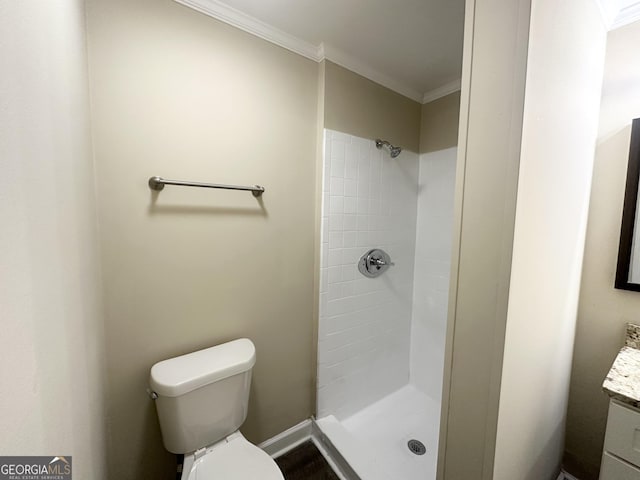 bathroom with vanity, toilet, ornamental molding, and a tile shower