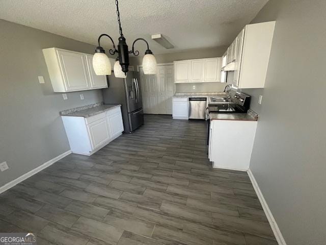 kitchen featuring white cabinets, appliances with stainless steel finishes, hanging light fixtures, and a notable chandelier