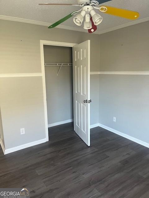 unfurnished bedroom with ceiling fan, dark wood-type flooring, crown molding, a textured ceiling, and a closet