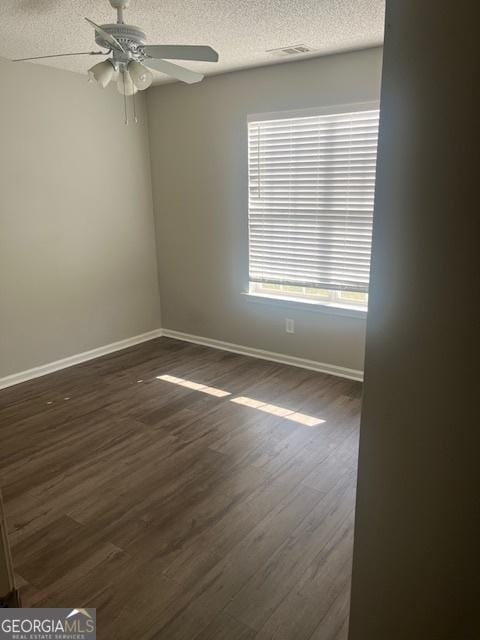 spare room featuring dark hardwood / wood-style flooring, a textured ceiling, ceiling fan, and a healthy amount of sunlight