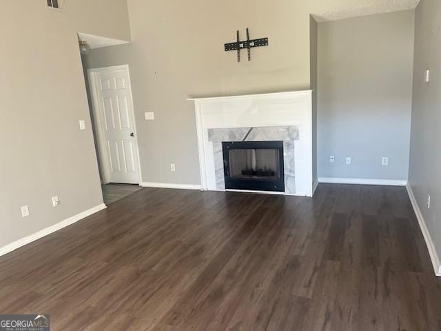 unfurnished living room with dark hardwood / wood-style flooring and a tiled fireplace