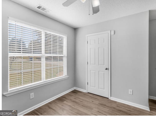 empty room featuring hardwood / wood-style floors, a textured ceiling, and ceiling fan