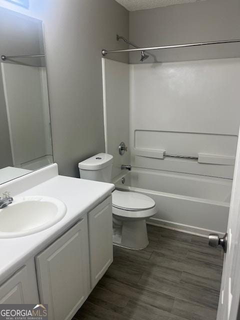 full bathroom with vanity, a textured ceiling, bathing tub / shower combination, hardwood / wood-style flooring, and toilet