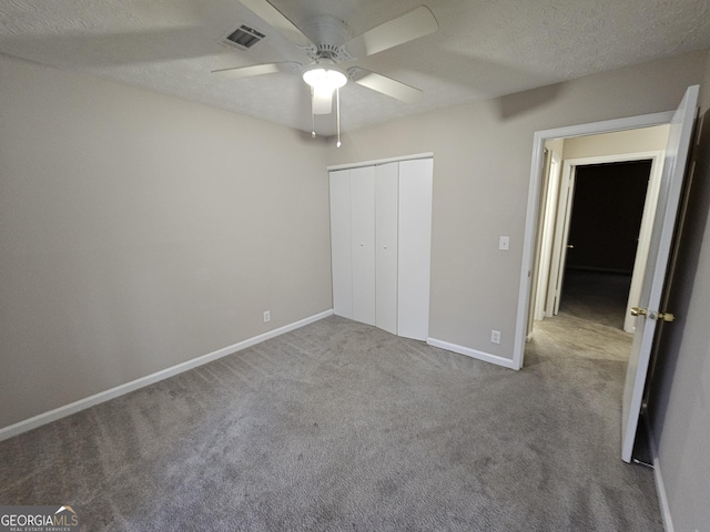 unfurnished bedroom featuring ceiling fan, light colored carpet, a textured ceiling, and a closet