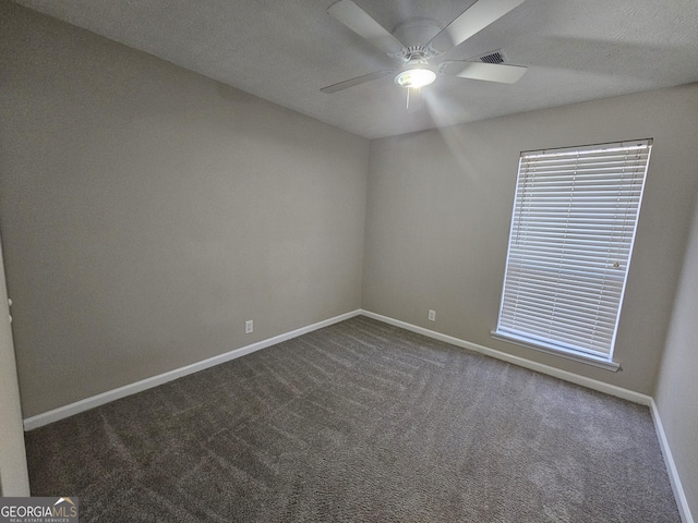 spare room with dark colored carpet, a textured ceiling, and ceiling fan