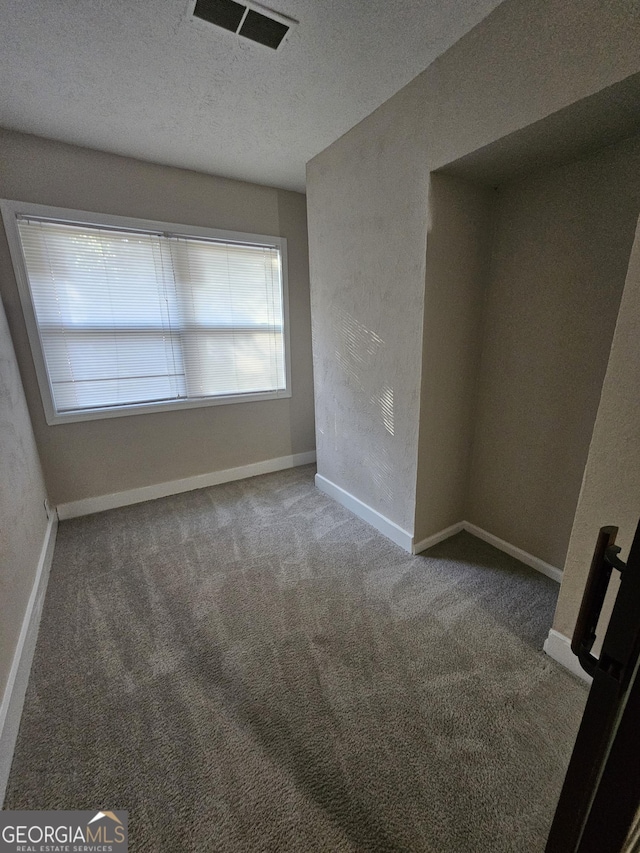 carpeted empty room with a textured ceiling