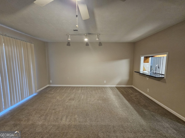 carpeted spare room featuring ceiling fan, sink, track lighting, and a textured ceiling