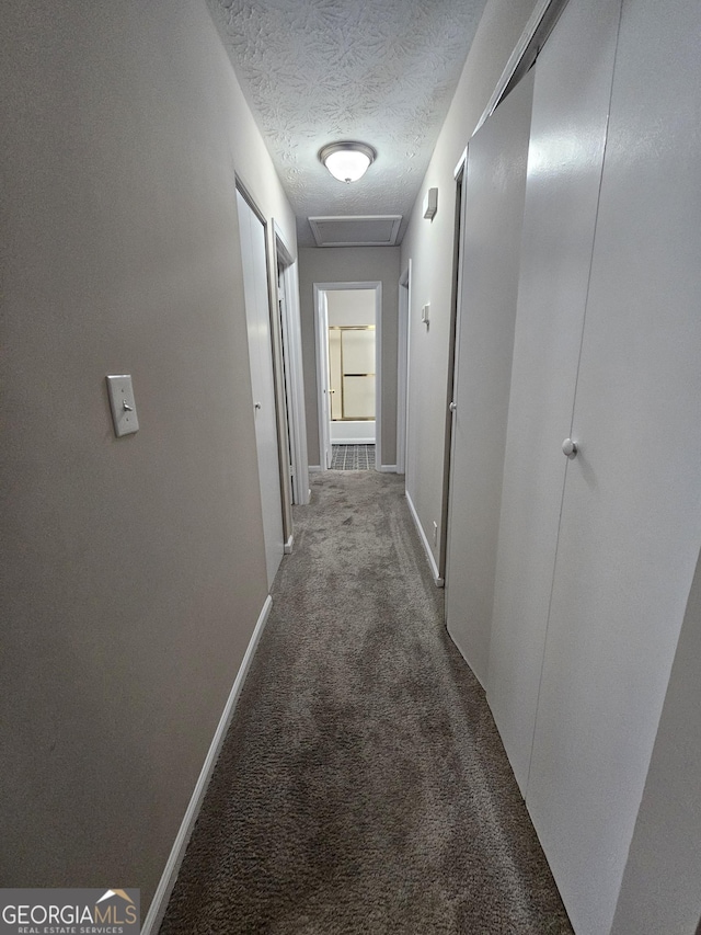 hallway with a textured ceiling and carpet floors