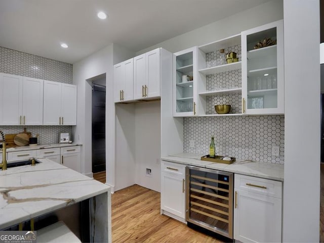 kitchen with light stone counters, white cabinetry, and wine cooler