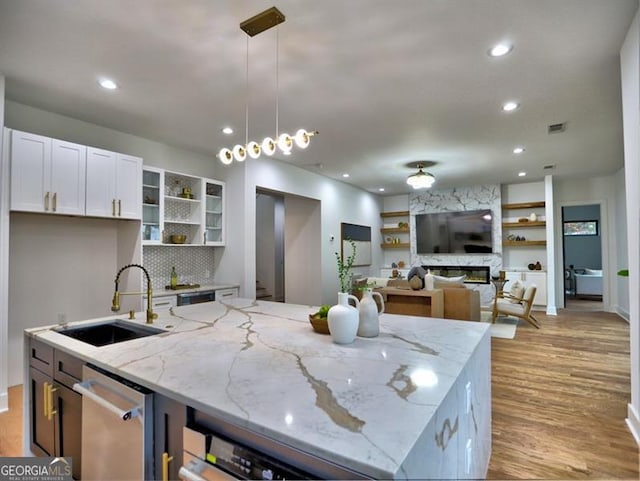 kitchen featuring white cabinets, pendant lighting, light stone counters, and sink