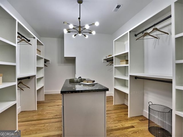 spacious closet featuring light hardwood / wood-style flooring and a notable chandelier