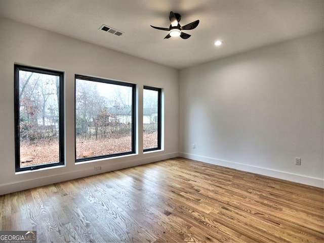 spare room featuring light wood-type flooring, a wealth of natural light, and ceiling fan