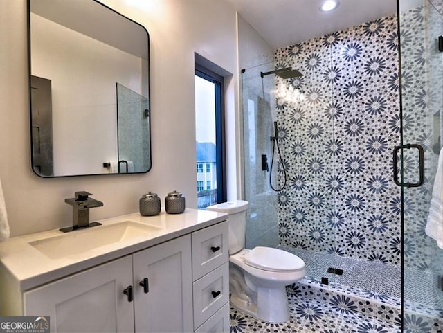 bathroom featuring a shower with door, vanity, and toilet