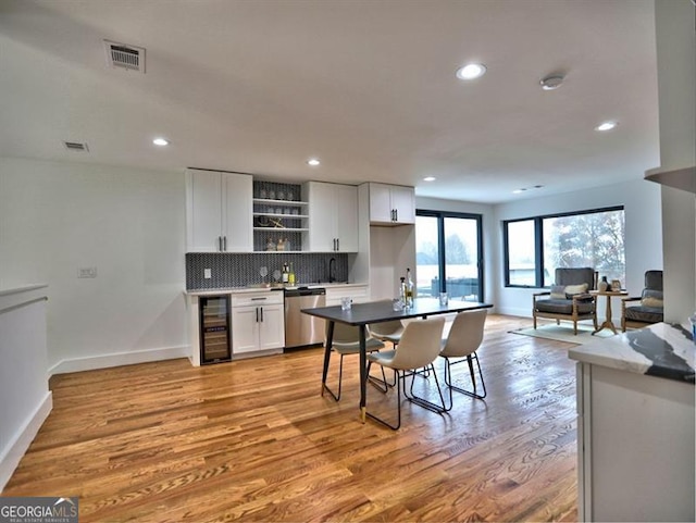 kitchen featuring wine cooler, white cabinetry, dishwasher, and light hardwood / wood-style flooring