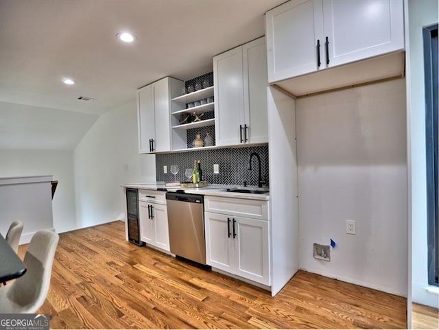 kitchen with tasteful backsplash, white cabinetry, dishwasher, and light hardwood / wood-style flooring