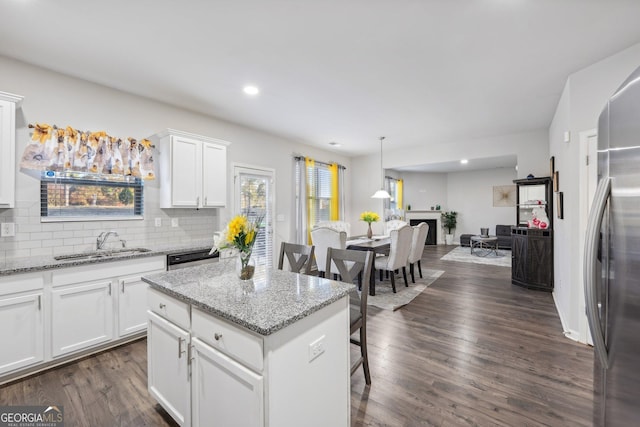 kitchen with dark hardwood / wood-style floors, a kitchen island, light stone counters, and white cabinetry