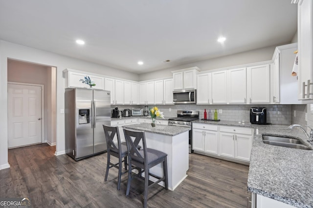 kitchen with dark hardwood / wood-style flooring, stainless steel appliances, sink, a center island, and white cabinetry