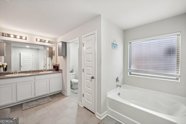 bathroom with a tub, vanity, and toilet