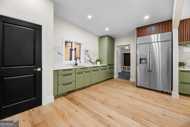 kitchen featuring light hardwood / wood-style flooring, built in refrigerator, green cabinetry, and sink