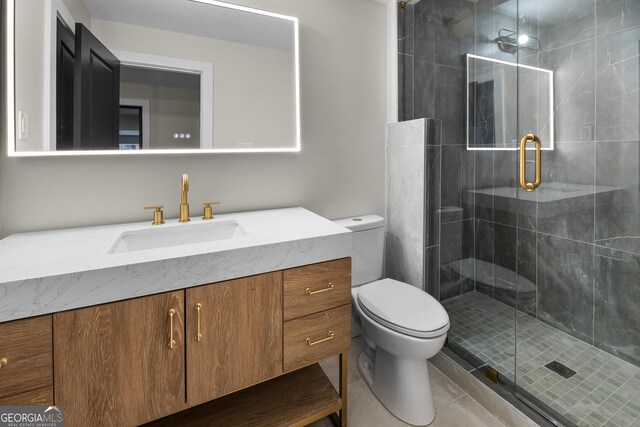 bathroom featuring tile patterned floors, a shower with door, vanity, and toilet