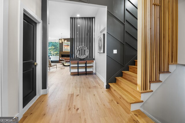 stairway with hardwood / wood-style floors, a large fireplace, and a chandelier