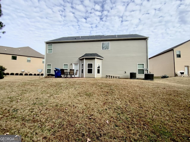 back of property featuring a lawn and central AC