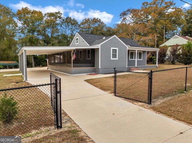 view of front of home with a front yard, a carport, and a sunroom