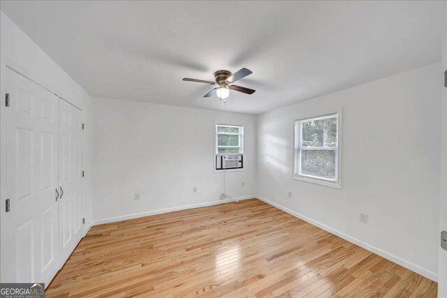 spare room featuring ceiling fan, cooling unit, and light wood-type flooring