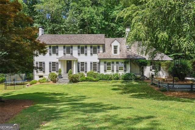 colonial inspired home with a trampoline and a front lawn