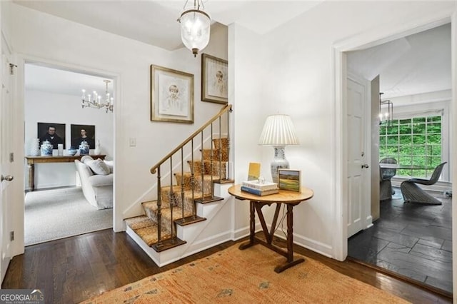 stairs with hardwood / wood-style floors and an inviting chandelier