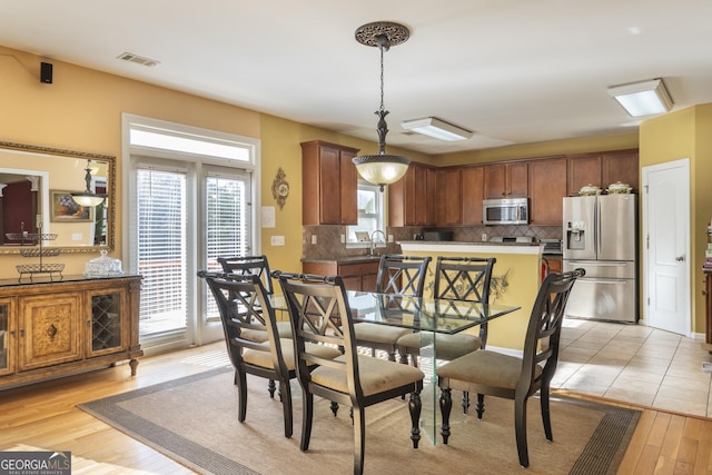 dining space featuring light hardwood / wood-style floors, sink, and a wealth of natural light