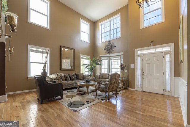 living room featuring a notable chandelier, a high ceiling, and light wood-type flooring