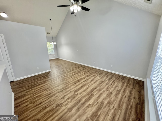 unfurnished living room featuring a textured ceiling, high vaulted ceiling, ceiling fan with notable chandelier, and hardwood / wood-style flooring