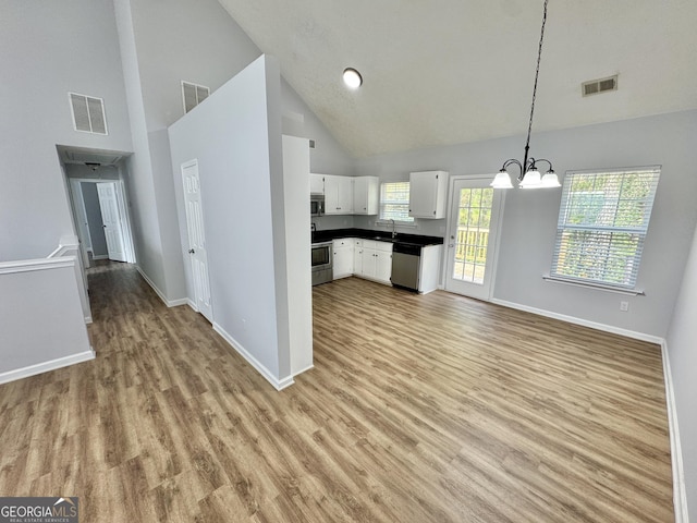 kitchen with white cabinetry, an inviting chandelier, high vaulted ceiling, pendant lighting, and appliances with stainless steel finishes