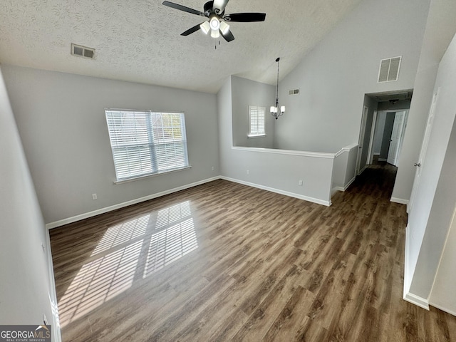 unfurnished living room featuring a textured ceiling, dark hardwood / wood-style flooring, high vaulted ceiling, and ceiling fan with notable chandelier