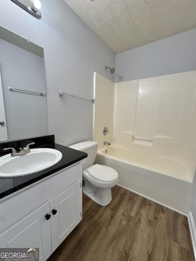 full bathroom featuring vanity, hardwood / wood-style floors, a textured ceiling, and toilet