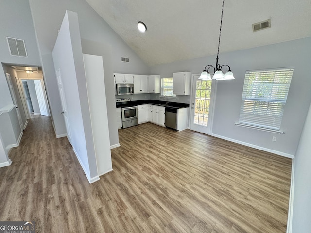 kitchen featuring hanging light fixtures, stainless steel appliances, high vaulted ceiling, light hardwood / wood-style floors, and white cabinets