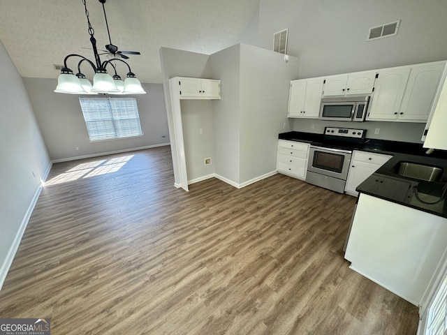 kitchen featuring a textured ceiling, stainless steel appliances, wood-type flooring, decorative light fixtures, and white cabinets