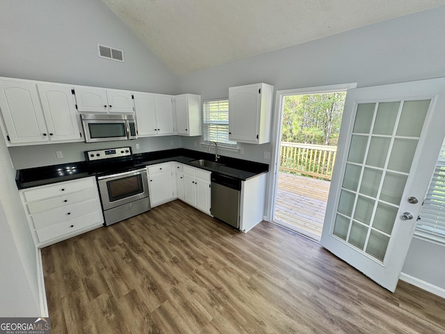 kitchen with high vaulted ceiling, white cabinets, sink, hardwood / wood-style flooring, and stainless steel appliances