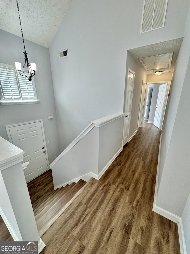 entrance foyer with a textured ceiling, dark hardwood / wood-style flooring, a chandelier, and vaulted ceiling