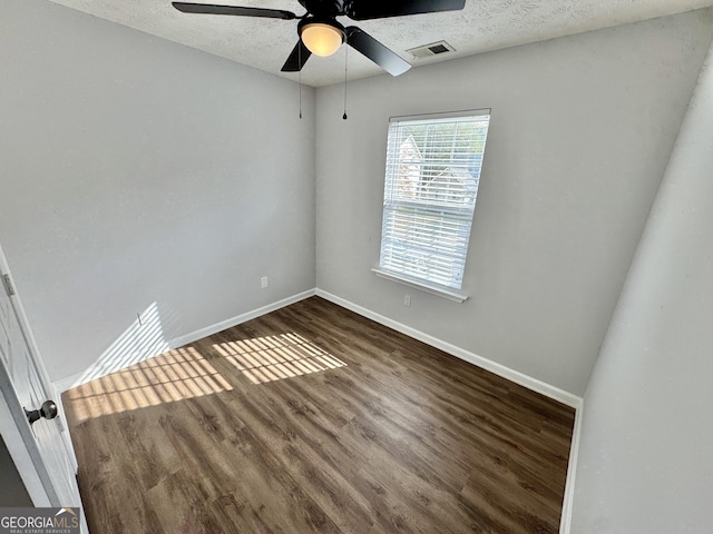 spare room with dark hardwood / wood-style floors, ceiling fan, and a textured ceiling