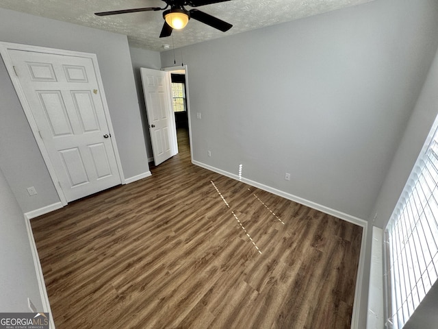 unfurnished bedroom with ceiling fan, dark hardwood / wood-style flooring, and a textured ceiling